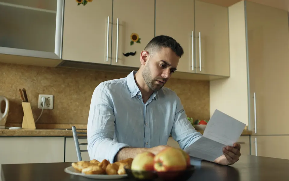 Hombre leyendo una carta en la mesa de la cocina